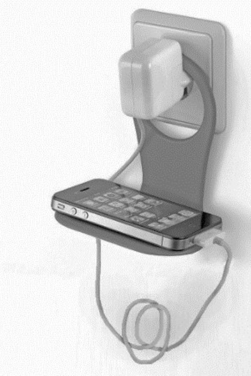 Smartphone auf kleinem Wandhalter beim Laden, Steckdose und Ladekabel sichtbar